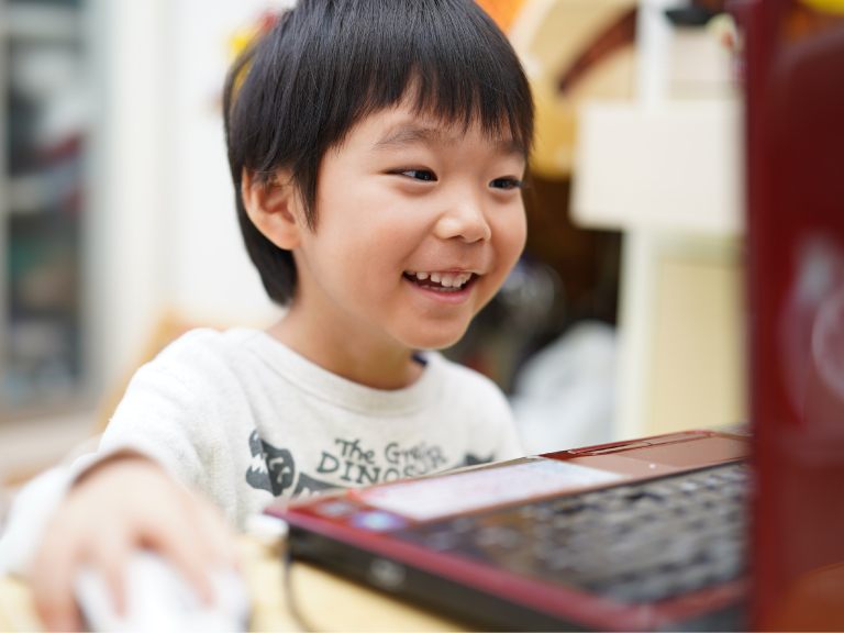 笑顔でパソコンを操作する子ども